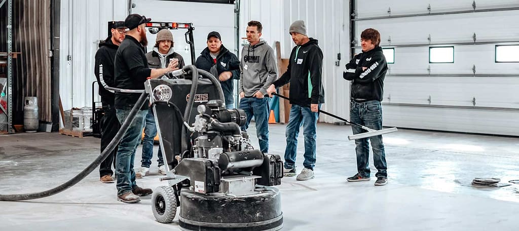 Trainer talking to a group of students in a concrete floor coating training class.