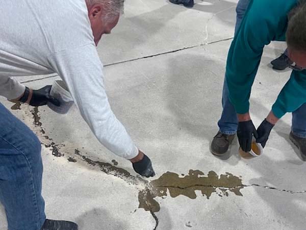 Two men applying concrete repair products to a floor.