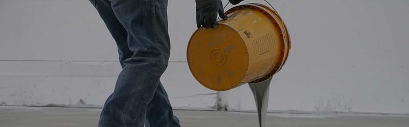 Person pouring a bucket of garage floor coating.